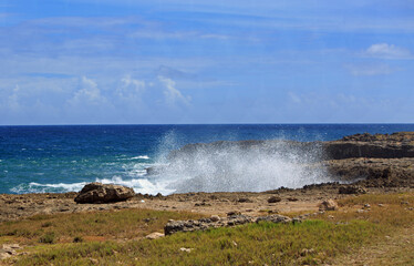 Rugged Coastline near Flower Cove in Barbados, with the waves crashing overthe cliff against a bright blue clear sky