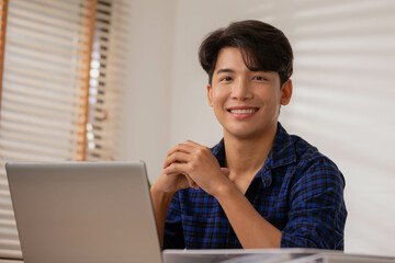 Asian entrepreneur At home, after a long day at the office, I sit and relax on my desk table, smiling and happy.