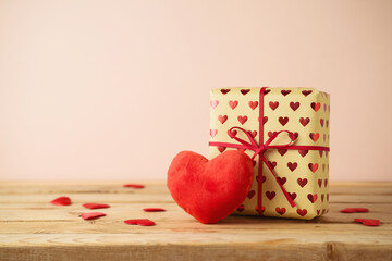 Valentine's Day concept with gift box and heart shape on wooden table over pink background