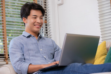 Business asian man watching and working online on desk table smile and happiness with laptop at home.