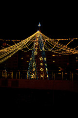 Long exposure night shot of a uniquely decorated main Christmas tree in the square after rain with reflection.