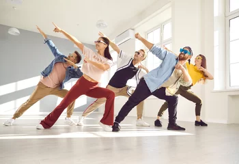 Gordijnen Group of happy, positive, cheerful, smiling people enjoying contemporary dance class. Young male and female dancers wearing trendy glasses and casual wear dancing together in light modern dance hall © Studio Romantic