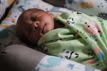 A newborn baby is sleeping comfortably with an adorable expression. Asian child two days old. 