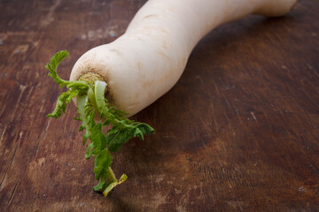 Daikon, east long white radish on brown background. Fresh organic vegan farm vegetables, seasonal harvest, healthy food.