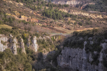 Petit pont enjambant un canyon étroit dans un massif calcaire, avec une voiture. Oppedette