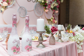 Decorated pink wedding presidium for just married, event organization. Beautiful flowers, champagne bottles, candles close up