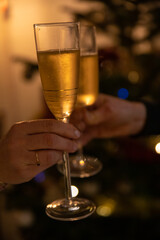 Deux mains tenant des coupes de champagne qui trinquent pour souhaiter de joyeuses fêtes, une bonne année. Pouvant illustrer également un cocktail, un vernissage ou une invitation à une réception. 