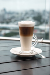 A glass of coffee latte on a table against a blurred background.