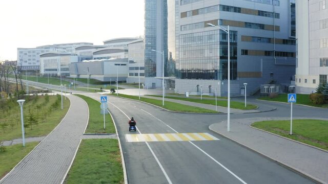 Aerial view of a man with amputated legs and arms drives on an electric wheelchair along the street in Far Eastern Federal University campus area