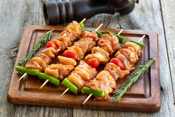 Chicken skewers on a wooden background. Close-up of raw chicken skewers marinated in tomato sauce. Horizontal view