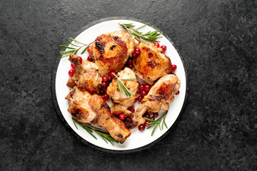 Various pieces of turkey baked with cranberries and rosemary on a stone background.
