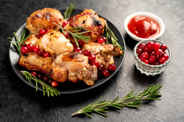Various pieces of turkey baked with cranberries and rosemary on a stone background.