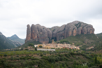 Naklejka na ściany i meble Small village on the hill of the mountain under the imposing rocks of the Mallos de Agüero in Huesca, Spain, Europe. Travel, Nature, Landscape, and trekking concept.