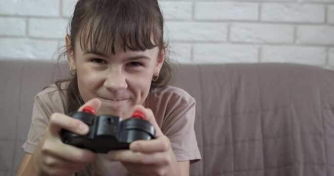 Free time with gamepads. An emotional young girl with gamepads play internet games in the room.
