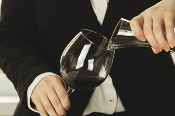 sommelier pours wine into a glass from a decanter after aeration