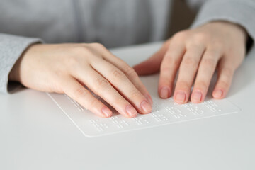 female hands touch the text for the blind braille