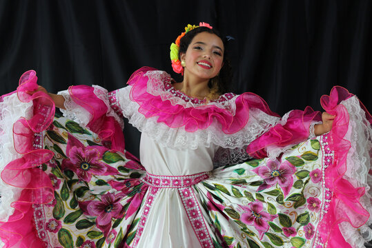 Portrait of young Colombian girl wearing traditional folklore Sanjuanero Huilense costume dress in pink and white with flowers for dancing