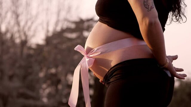 belly of a pregnant woman with a pink bow that heralds the birth of a baby girl