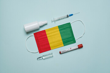 Blood tube for test detection of virus Covid-19 Omicron Variant with positive result, medicine mask with Guinea flag superimposed and vaccine.  New Variant of the Covid-19 Omicron