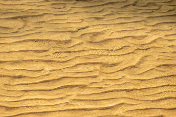 Fototapeta na wymiar Golden sand under water during sunset as background
