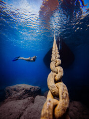 Underwater Photo of free diver girl with boat yacht chain in dark blue sea, Cyprus, ocean lover,...