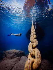 Gordijnen Onderwaterfoto van gratis duikermeisje met bootjachtketting in donkerblauwe zee, Cyprus, oceaanliefhebber, snorkelen © og.videography