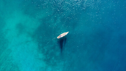 Drone aerial view of a sailing boat on a blue ocean sea waters.