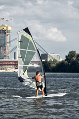 Naklejka premium Windsurfer surfing on a windy day at the city river.