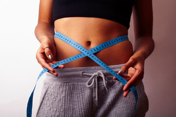woman measuring waist with tape on knot, african tan isolated