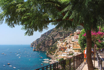 Arched tree framing the colourful houses of Positano meeting the sea, on the Amalfi coast, Italy.