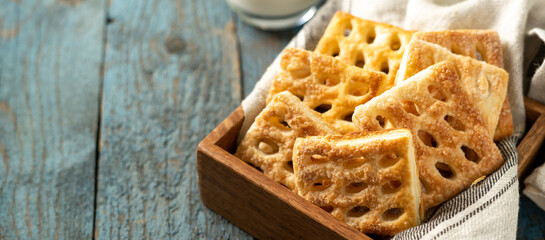 Puff cookies square in a wooden box on a blue wooden culinary background. Delicious homemade sweet pastries closeup	