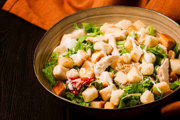 Fresh traditional Caesar salad, with chicken, on a wooden background,Top view, toned, horizontal no people,
