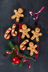 Gingerbread Man, Christmas honey ginger cookies with cinnamon and nutmeg on a serving board on a red linen napkin on a dark gray background. Top view