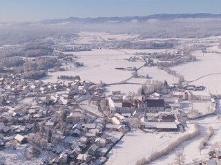 Fototapeta na wymiar AERIAL: Flying high above a quiet village in the idyllic wintry countryside.