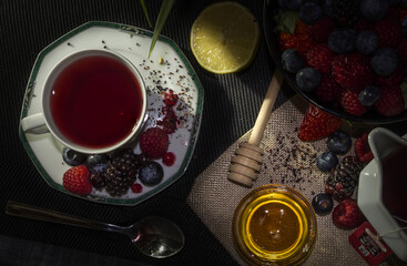 Hot red berry tea with honey and fruits on black background. overhead view