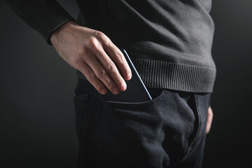 Man putting smartphone in pocket of jeans.