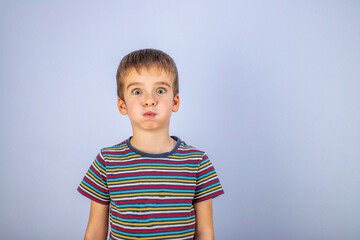 The boy in the striped T-shirt puffed out his cheeks. Emotions on the face. Blue background. Copy space