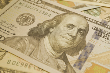American paper money. A $100 bill with focus on eyes of Benjamin Franklin. US banknotes close-up. Business economy and the USA dollar. Light olive tinted background. Macro
