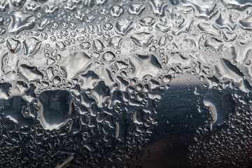 Drops of water on an aluminum beverage can, waste in nature paired with the existential element water, threatened, scarce, fascinatingly beautiful in its changing manifestations.
