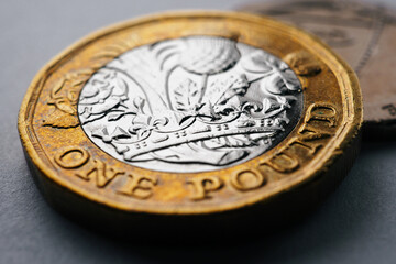 British money lies on a dark surface. 1 pound sterling coin close up. Focus on the crown. Economy and banking in England. Macro