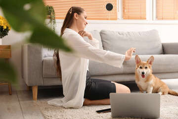 Young woman with cute Corgi dog sitting on floor at home
