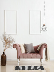 Pink armchair with pillows, plaid, vase and tree branches near light wall