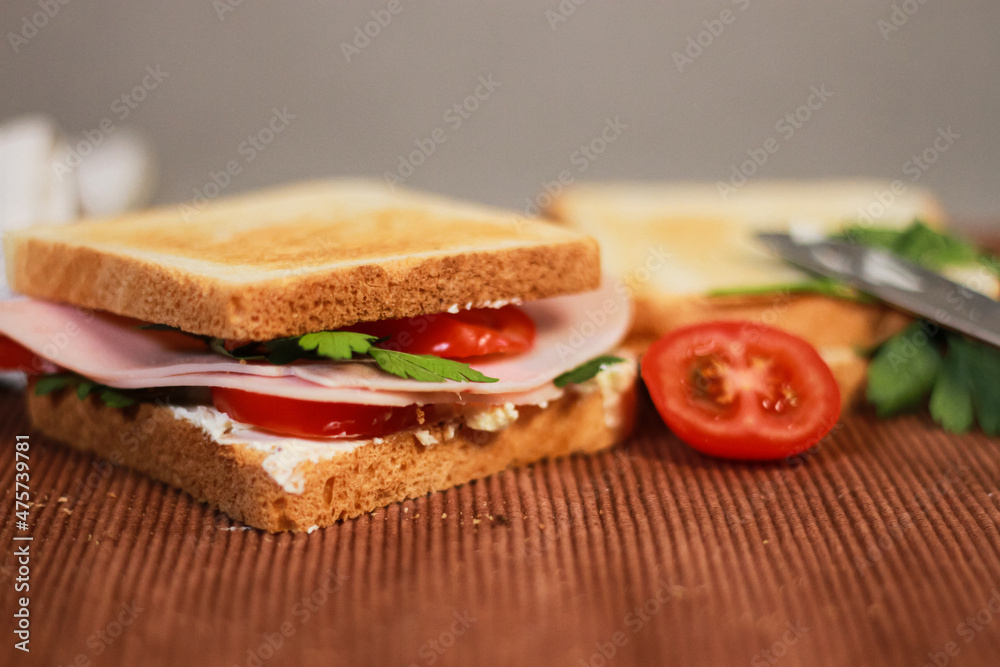 Wall mural Closeup of sandwiches with toast bread, tomatoes, ham, and parsley.