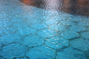 Turquoise blue bottom of a fountain full of water photographed during the daytime on a sunny day....