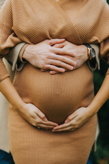 Vertical shot of a pregnant woman with a man holding the belly