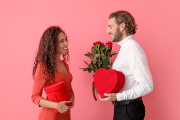 Happy young couple with gifts and flowers on color background. Valentine's Day celebration