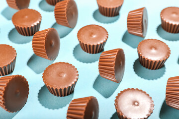 Tasty peanut butter cups on color background