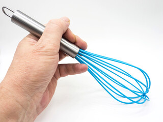 blue whisk for whipping on a white plate in hand