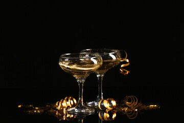 Glasses of champagne and serpentine on dark background