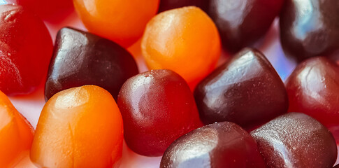 Selective focus.Close-up texture of red, orange and purple multivitamin gummies on white background